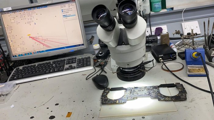 A logic board under the microscope at the repair bench